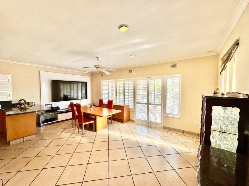 Spacious open-plan living and dining area featuring tiled flooring, recessed lighting, and plantation shutters, with direct access to the outdoor area.