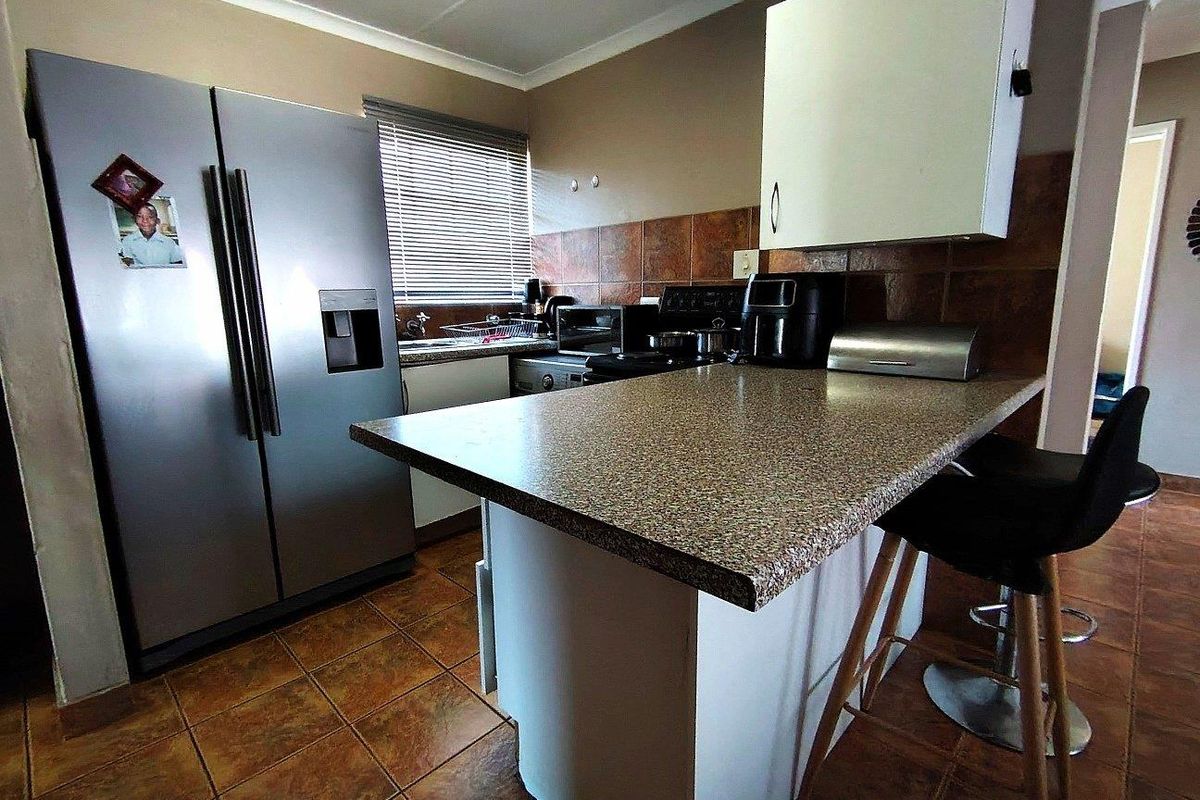 A functional kitchen featuring a breakfast bar, tiled flooring, tiled backsplash, and built-in cabinetry with a neutral color scheme.