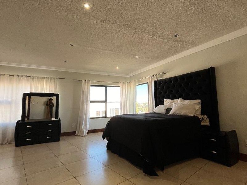 Spacious bedroom featuring large format floor tiles, recessed lighting, and a textured ceiling finish with ample natural light from multiple windows.
