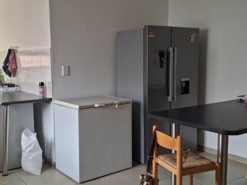 A functional kitchen area featuring tiled flooring, laminate countertops, and built-in cabinetry with a tiled backsplash.