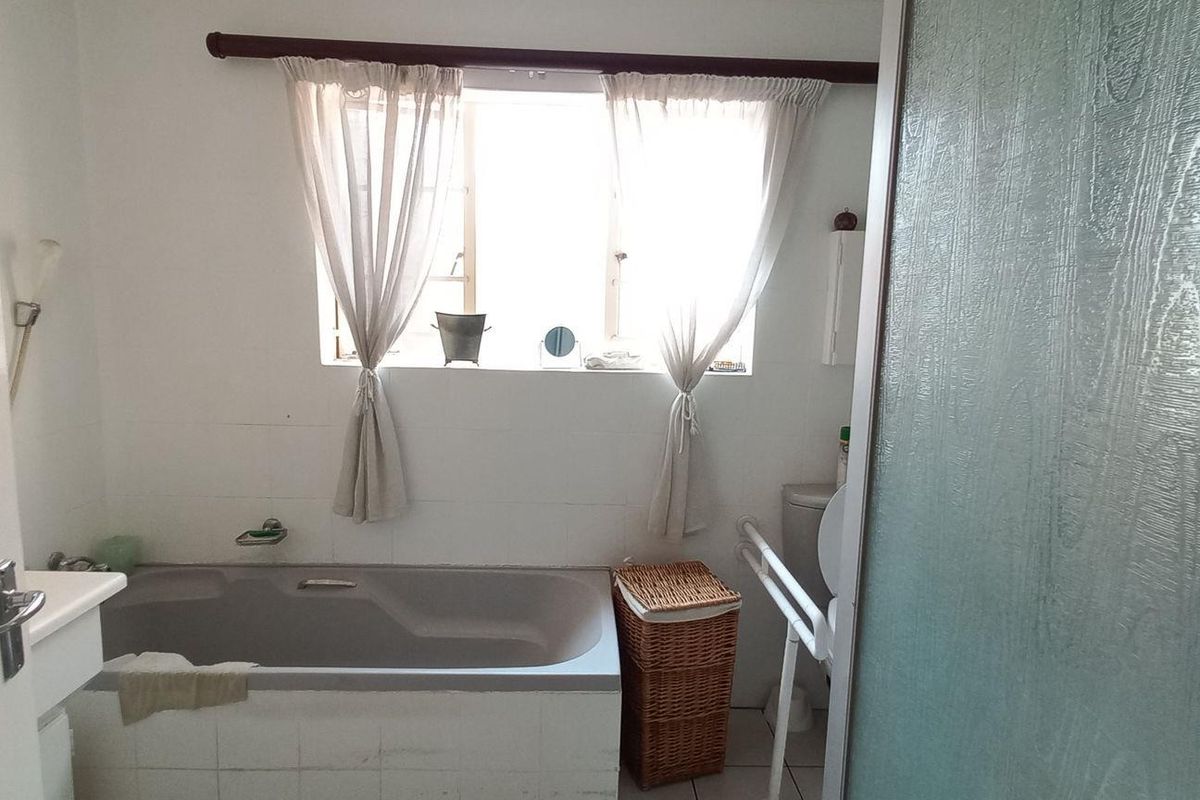 A functional bathroom featuring a built-in bathtub, tiled walls, and a window providing natural light.