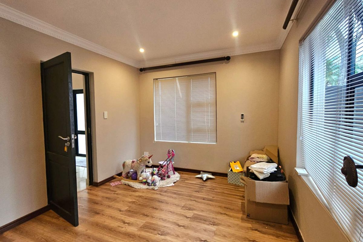 A bedroom featuring laminate flooring, neutral wall tones, recessed downlighting, and venetian blinds on the windows.