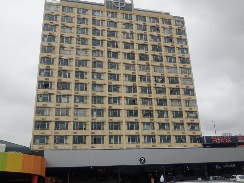 A multi-story apartment building facade featuring numerous windows and ground-level commercial retail space.