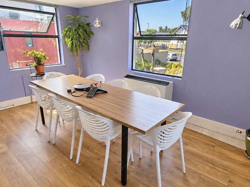 A functional office space featuring laminate flooring, wall-mounted air conditioning, and large windows providing natural light.
