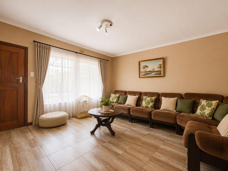A well-maintained living room featuring neutral wall tones, tiled flooring, and a large window that allows for ample natural light.