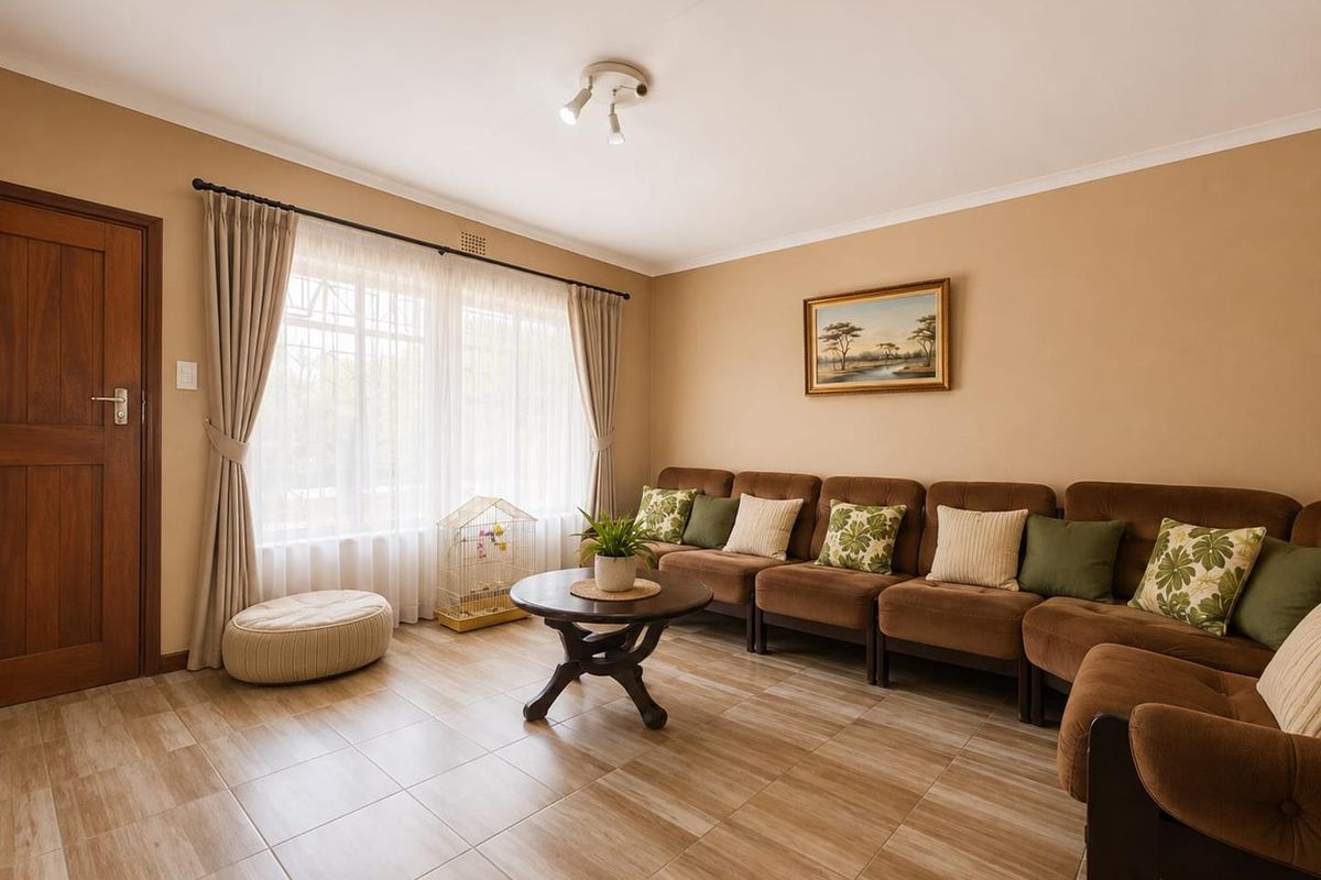 A well-maintained living room featuring neutral wall tones, tiled flooring, and a large window that allows for ample natural light.