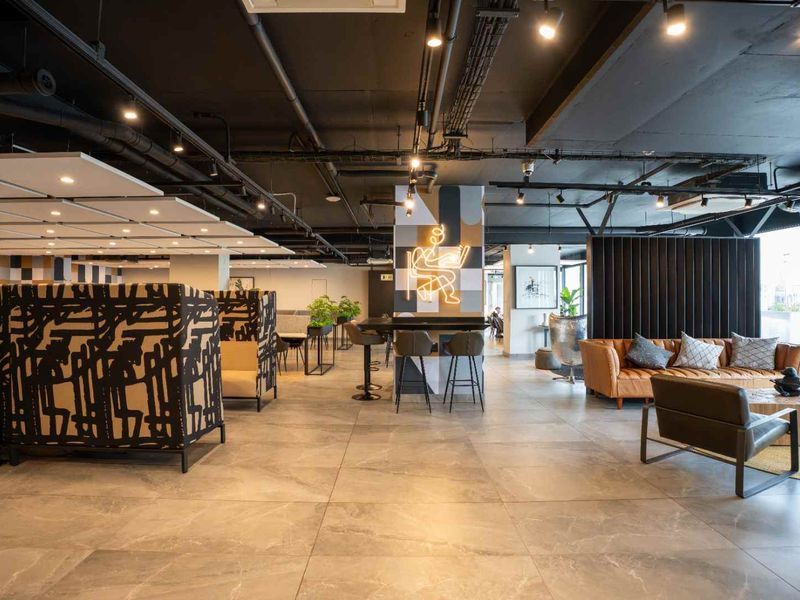 Modern open-plan communal area featuring industrial-style exposed ceilings, track lighting, and large-format porcelain tile flooring with a contemporary aesthetic.