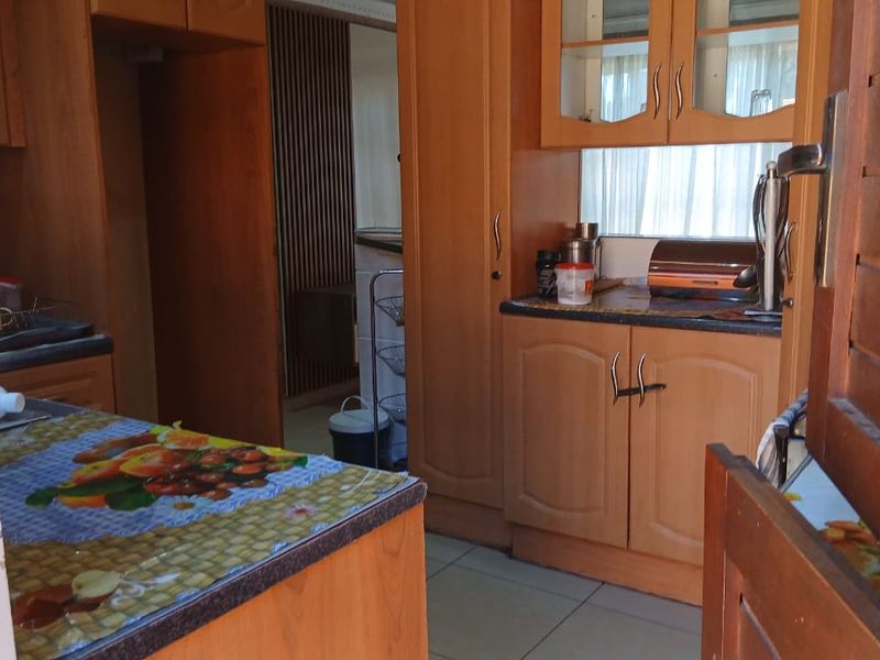A functional kitchen featuring traditional wooden cabinetry, laminate countertops, and tiled flooring, offering a classic layout with ample storage space.