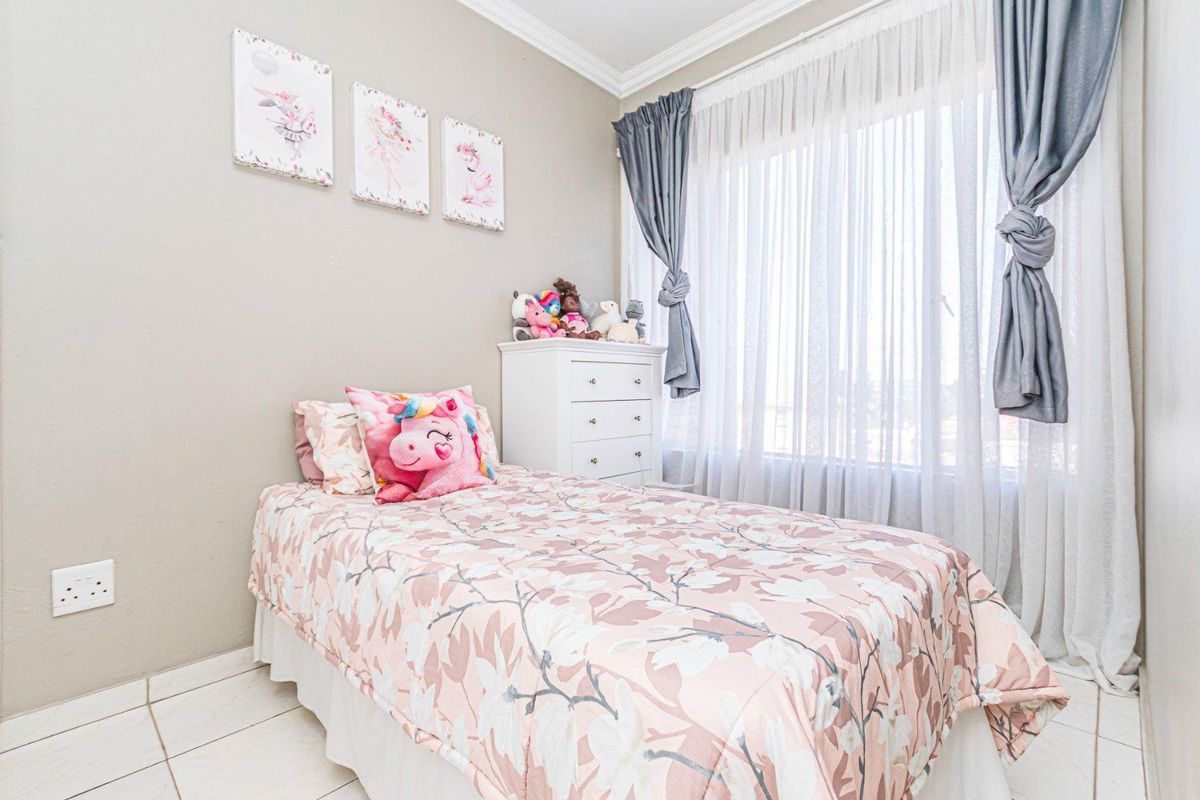 A bright and well-maintained bedroom featuring tiled flooring, neutral wall tones, and large windows with elegant curtain treatments.