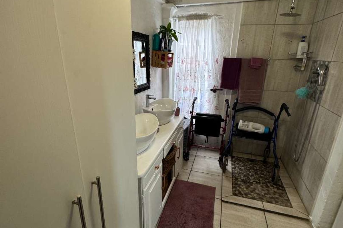 A functional bathroom featuring a double vanity with vessel sinks, a walk-in shower with rainfall showerhead, and tiled flooring.