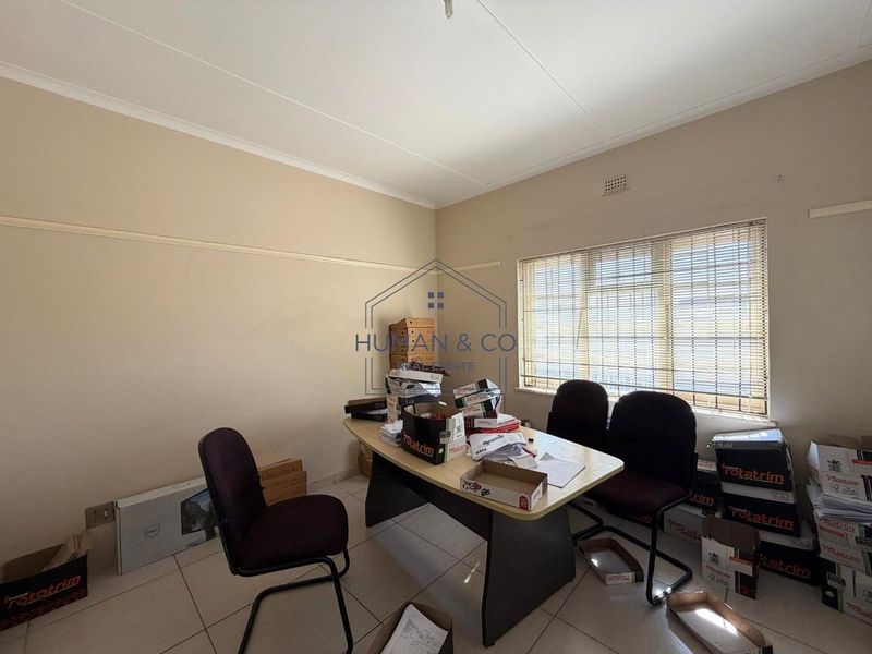 A functional office space featuring tiled flooring, neutral wall finishes, and venetian blinds, suitable for a professional workspace or study.