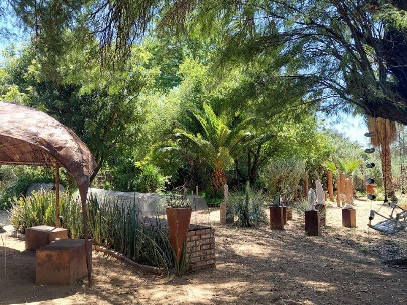 A spacious, mature garden area featuring established trees, a brick planter, and natural landscaping, providing a serene outdoor environment.