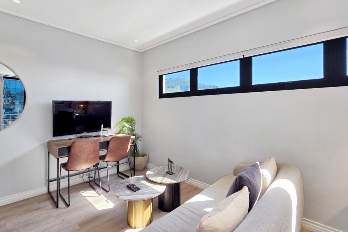 A bright and modern living area featuring light laminate flooring, recessed downlighting, and a horizontal clerestory window providing natural light.