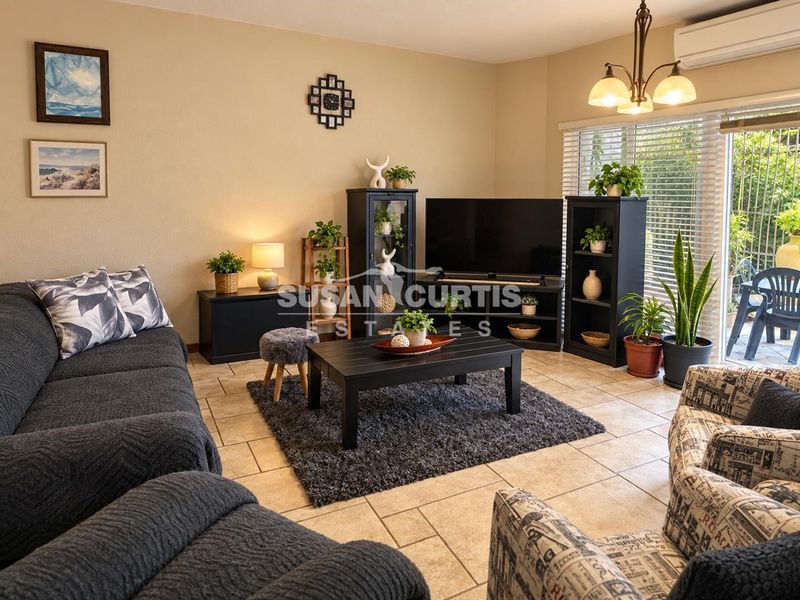 A comfortable living room featuring tiled flooring, a wall-mounted air conditioning unit, and sliding glass doors that provide access to the outdoor patio area.