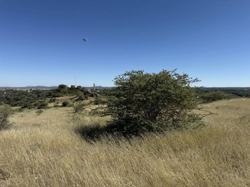 A scenic view of the vacant residential land featuring natural grassland and native vegetation under a clear blue sky.