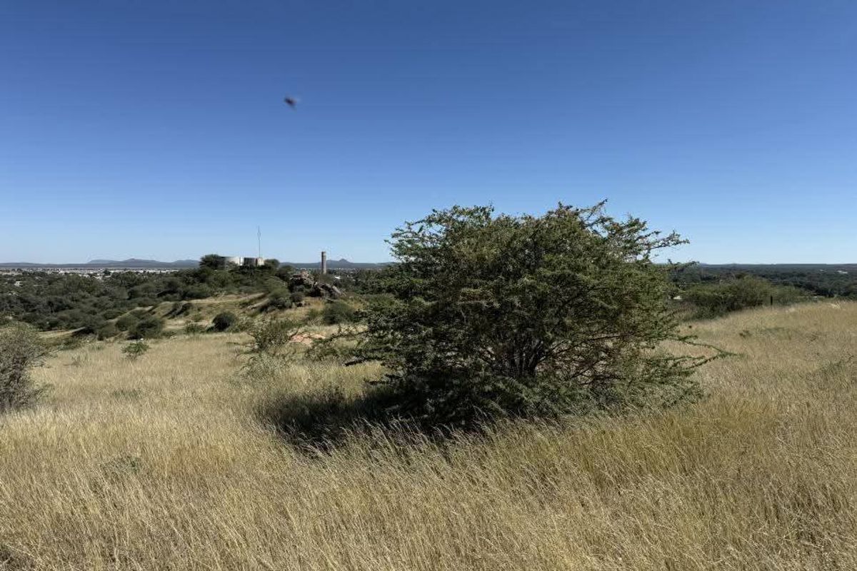 A scenic view of the vacant residential land featuring natural grassland and native vegetation under a clear blue sky.
