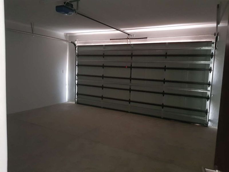 A clean, empty double garage featuring a sectional automated garage door and smooth concrete flooring.