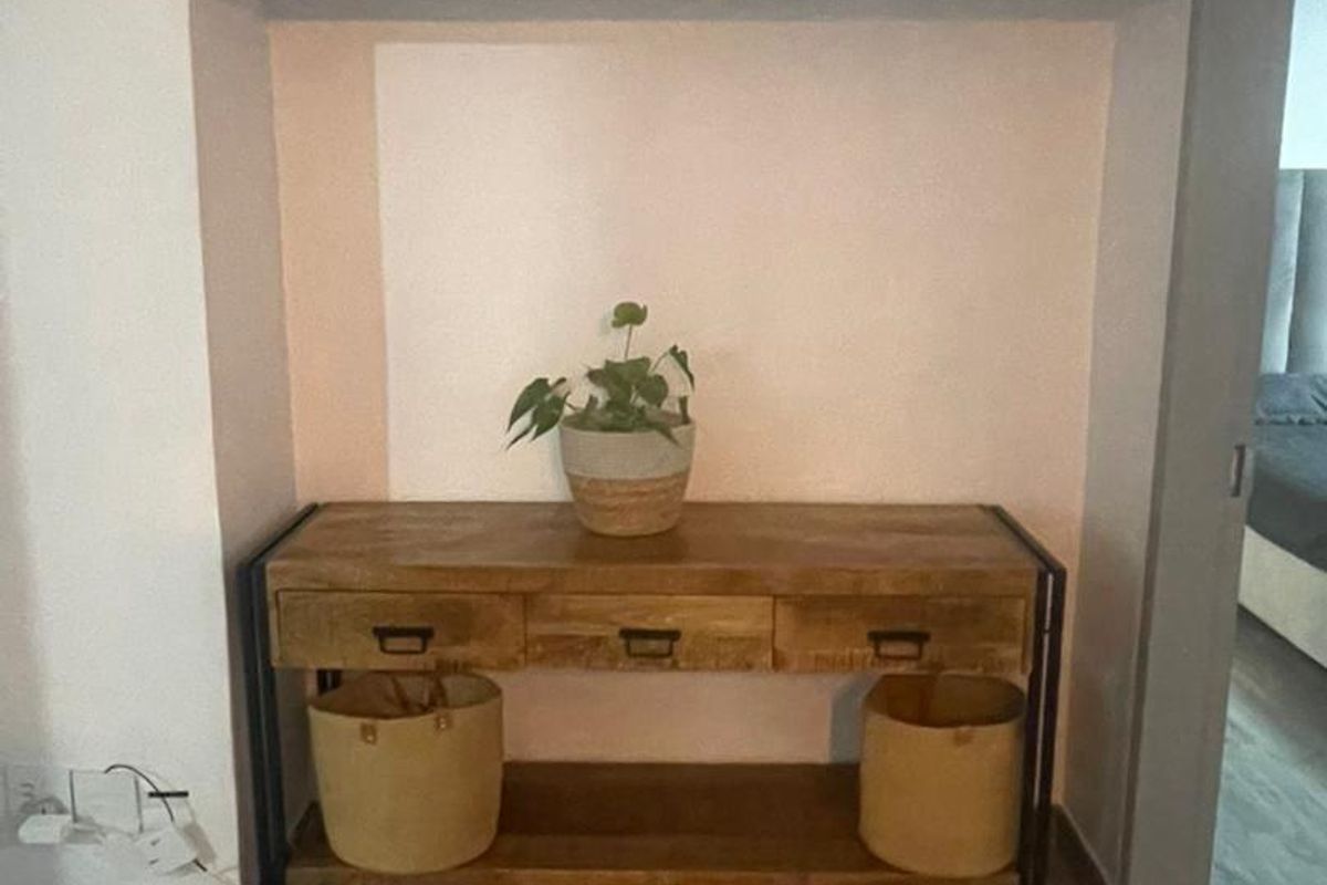A living area featuring a built-in overhead storage cabinet and light-toned laminate flooring.