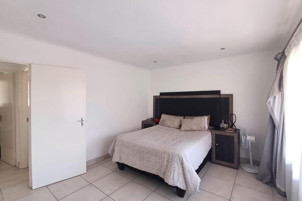 A bedroom featuring neutral floor tiles, recessed ceiling lighting, and a built-in headboard unit.