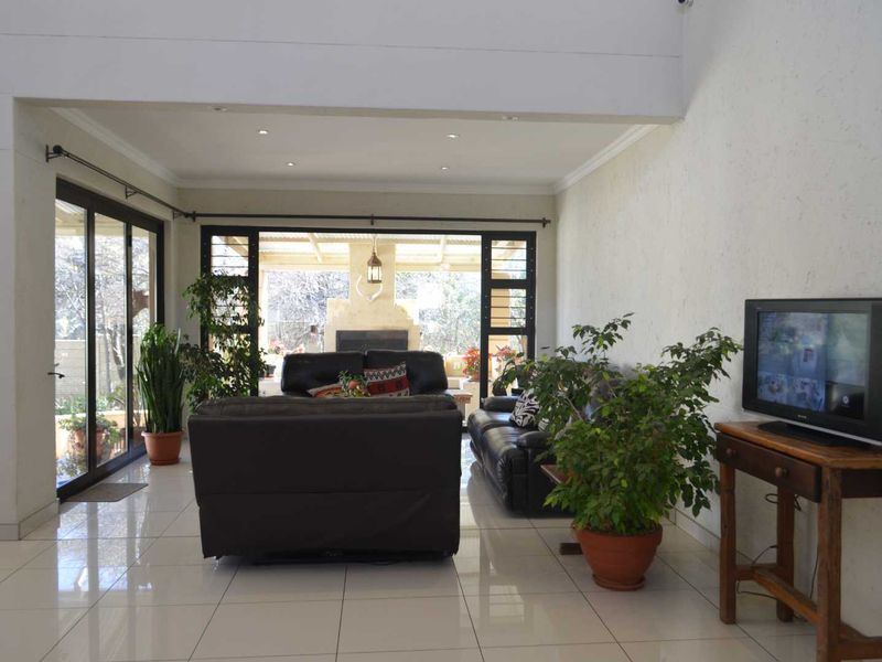 Spacious living room featuring large format floor tiles, double volume ceilings, and expansive sliding glass doors providing seamless access to the outdoor patio area.