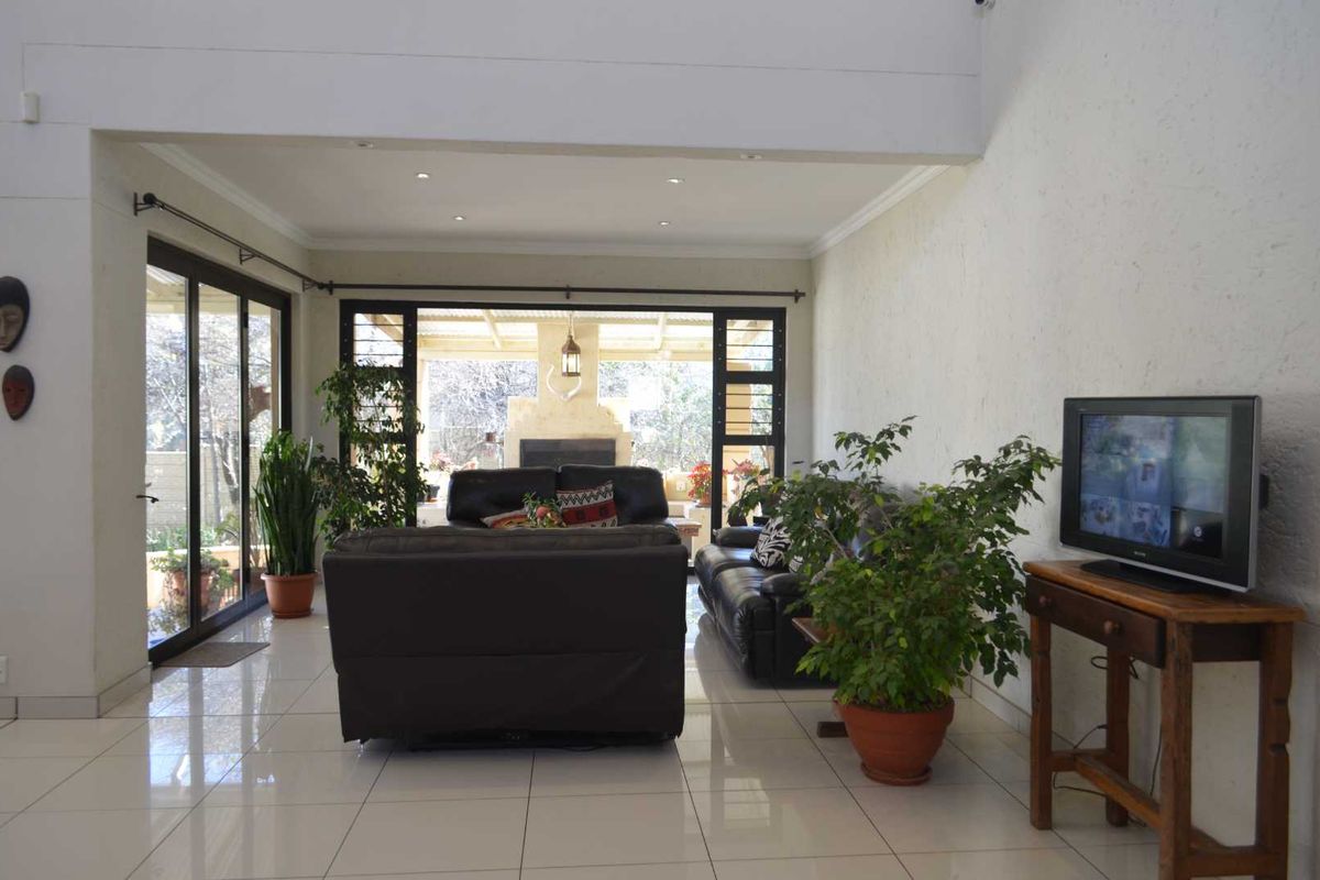 Spacious living room featuring large format floor tiles, double volume ceilings, and expansive sliding glass doors providing seamless access to the outdoor patio area.