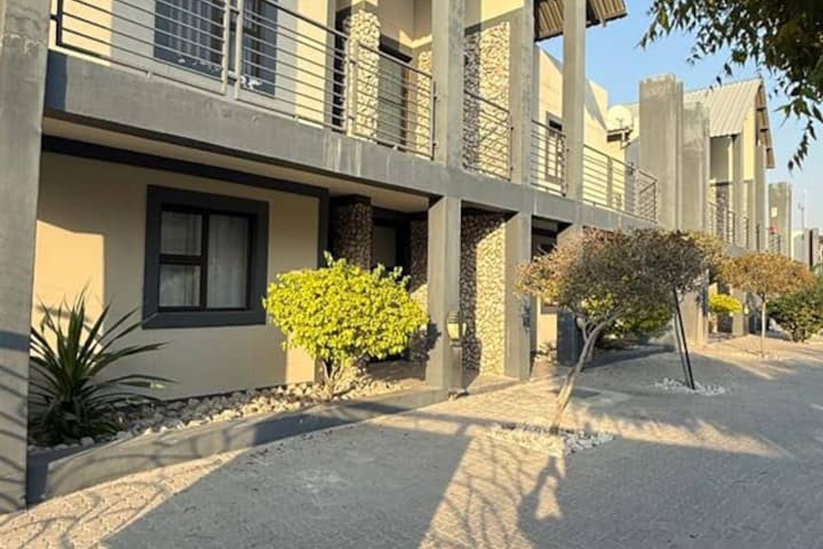 Modern apartment complex exterior featuring stone cladding, metal balcony railings, and a paved driveway with well-maintained structural finishes.