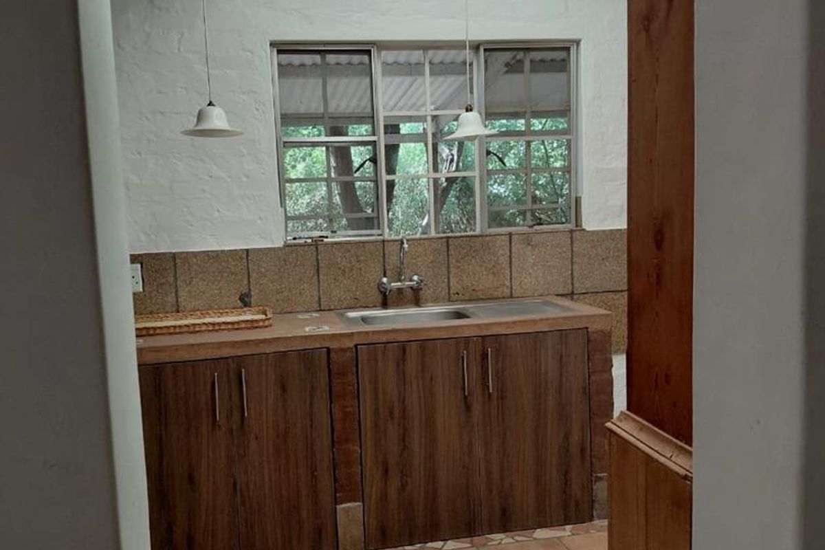 A functional kitchen area featuring built-in cabinetry, a stainless steel sink, and tiled finishes, awaiting updates to modernize the space.
