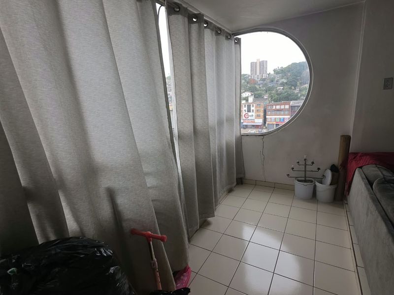 Enclosed balcony area featuring tiled flooring and a distinctive circular window with views of the surrounding neighborhood.