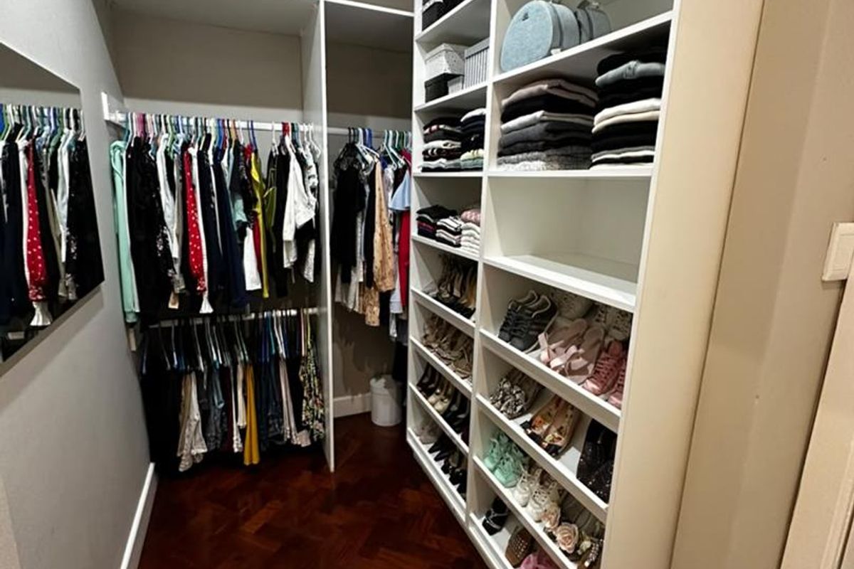 A walk-in closet featuring extensive built-in shelving, hanging rails, and classic parquet flooring.