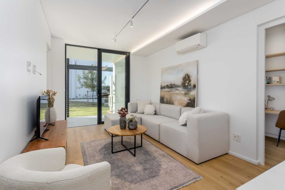Modern living room featuring timber flooring, recessed ceiling lighting, a split-system air conditioner, and a sliding glass door leading to an outdoor area.