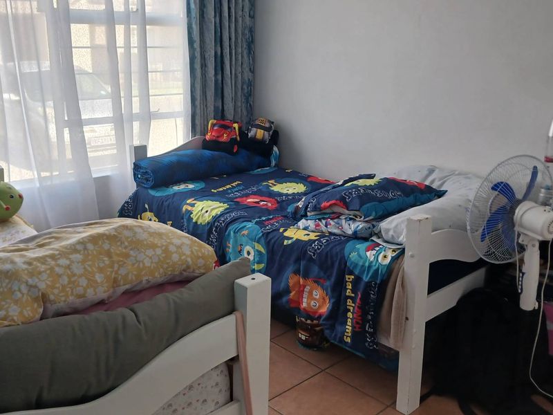 A bedroom featuring tiled flooring and large windows with curtain tracks, providing natural light to the space.