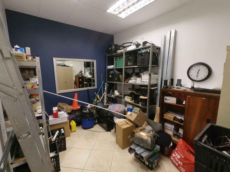 A utility or storage room featuring tiled flooring and recessed ceiling lighting, currently utilized for equipment and supply storage.