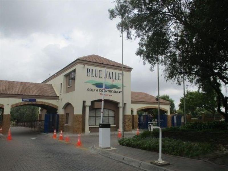 The main entrance gatehouse of Blue Valley Golf & Country Estate, featuring a secure boom gate access point and paved driveway.