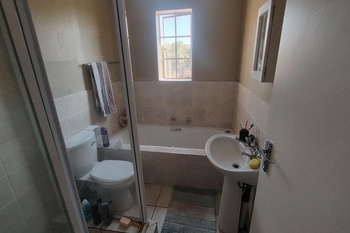 A functional bathroom featuring a built-in bathtub, pedestal basin, toilet, and a separate shower enclosure with tiled finishes.