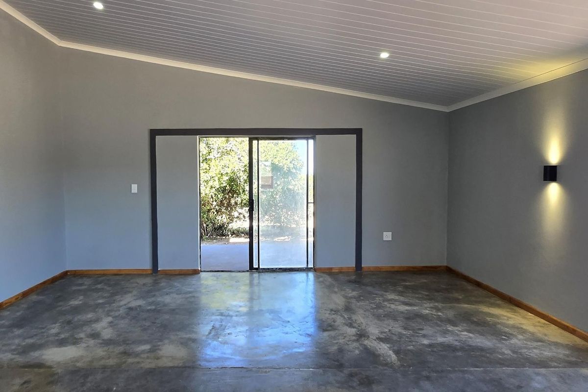Spacious living area featuring polished concrete floors, a raked ceiling with recessed lighting, and sliding glass doors providing access to the outdoor space.