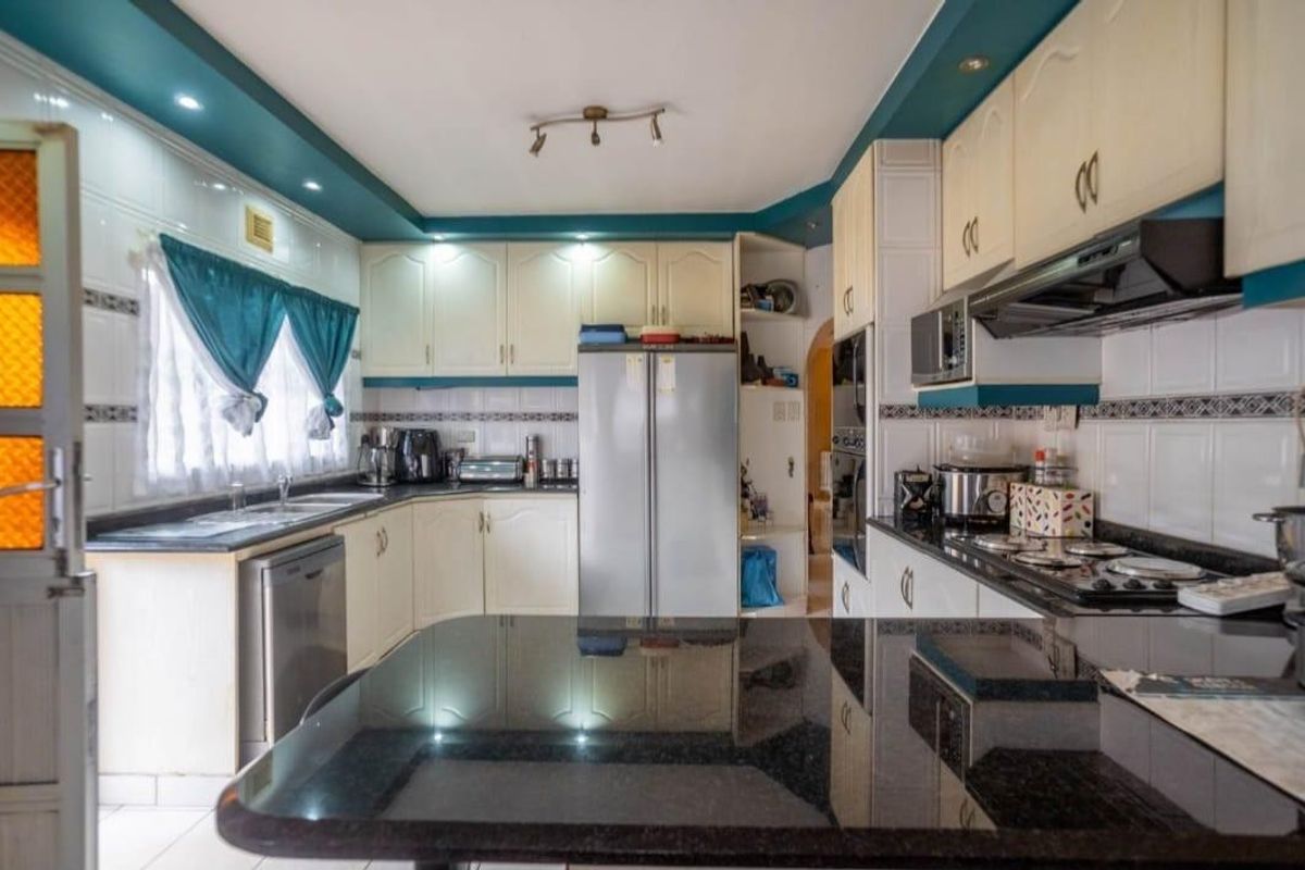 Functional kitchen featuring ample built-in cabinetry, granite countertops, a gas hob, extractor fan, and integrated oven, offering a practical layout for daily cooking.