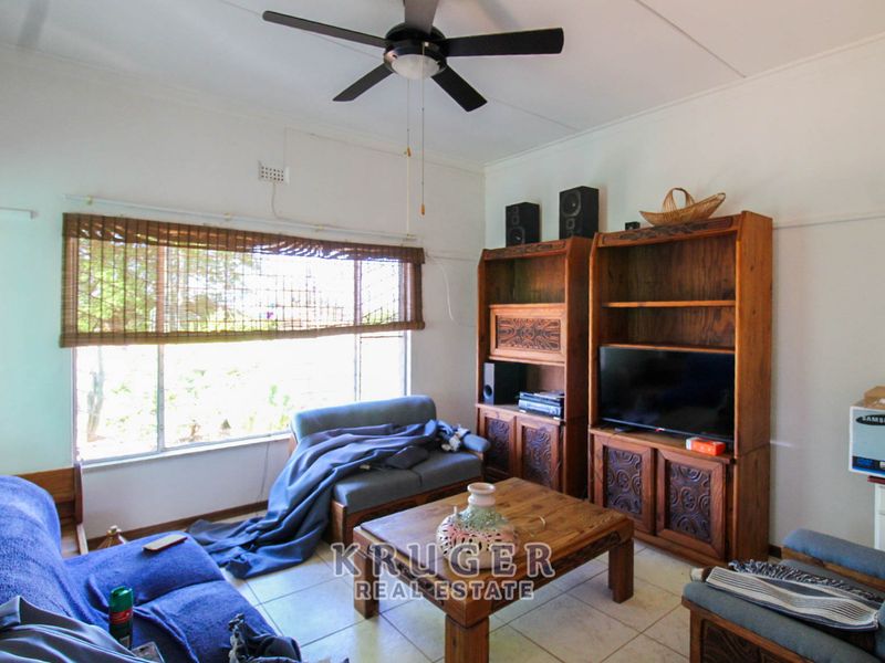 A living room featuring tiled flooring, a ceiling fan, and a large window providing natural light.