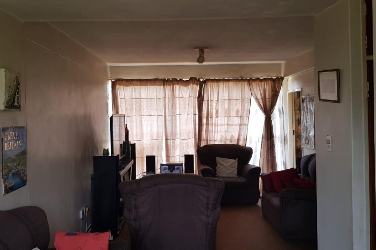 A living room area featuring carpeted flooring and large window curtains, requiring cosmetic updates to improve the overall aesthetic and condition.