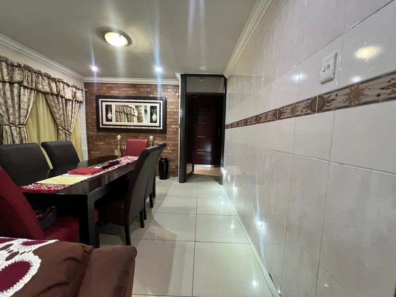 Dining room featuring an exposed brick feature wall, tiled flooring, and decorative wall tiling with integrated lighting.