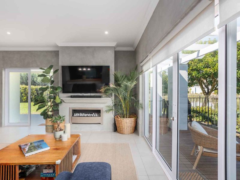 Modern living room featuring a built-in fireplace, sleek tiled flooring, and large sliding glass doors that provide seamless access to the outdoor patio area.