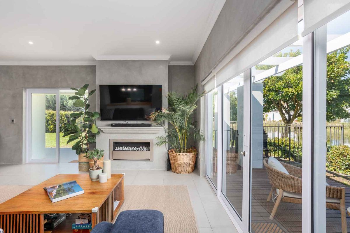 Modern living room featuring a built-in fireplace, sleek tiled flooring, and large sliding glass doors that provide seamless access to the outdoor patio area.