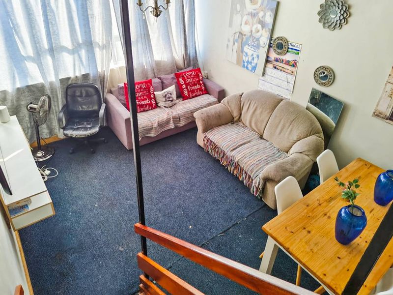 An open-plan living and dining area featuring carpeted flooring and a staircase railing, offering a functional layout for daily living.