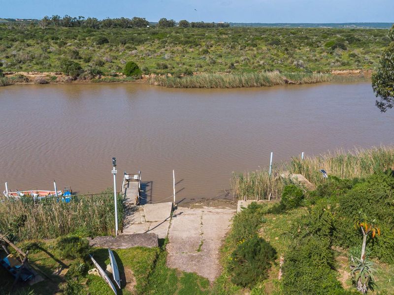 Aerial view of a private riverfront property featuring a concrete boat ramp and wooden jetty, offering direct access to the water.