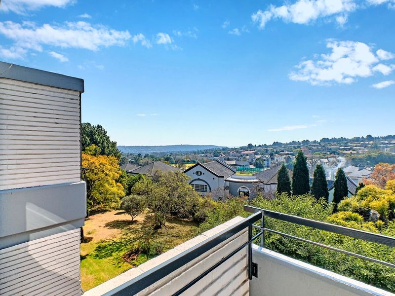 A scenic elevated view overlooking a residential neighborhood and lush green gardens from a private apartment balcony.