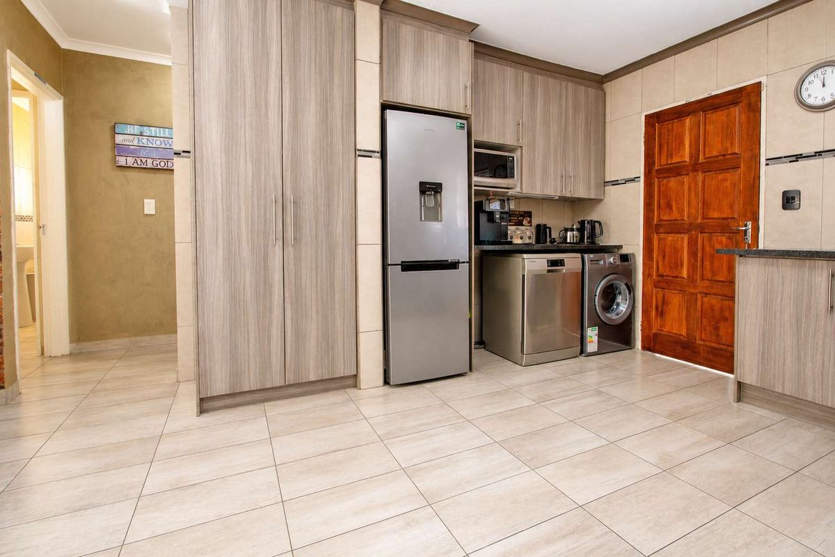 A functional kitchen featuring modern wood-grain cabinetry, tiled flooring, stone countertops, and integrated appliance spaces, providing a clean and practical culinary environment.