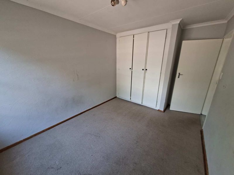 An empty bedroom featuring built-in wardrobes, carpeted flooring, and coved ceilings, presenting a blank canvas for potential renovation or restyling.