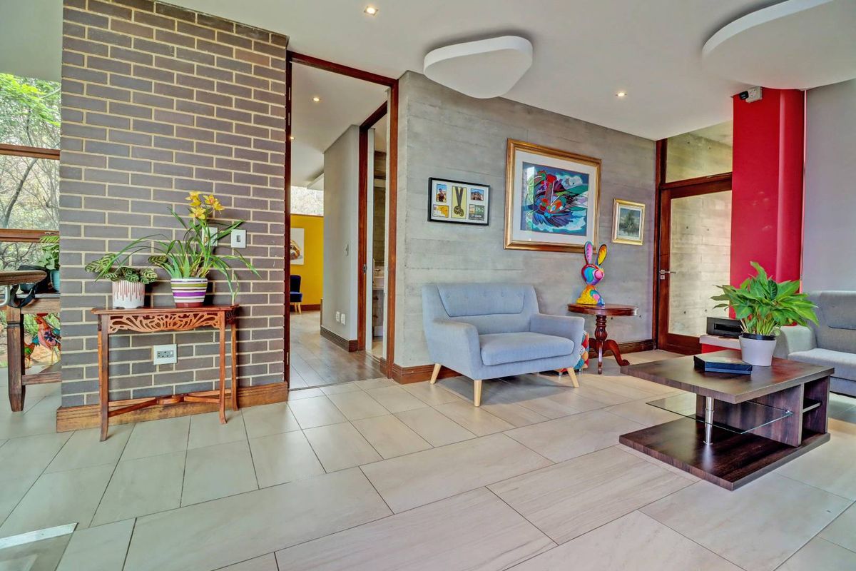 A modern living area featuring a blend of exposed brick and concrete walls, tiled flooring, and recessed lighting, creating a contemporary industrial aesthetic.