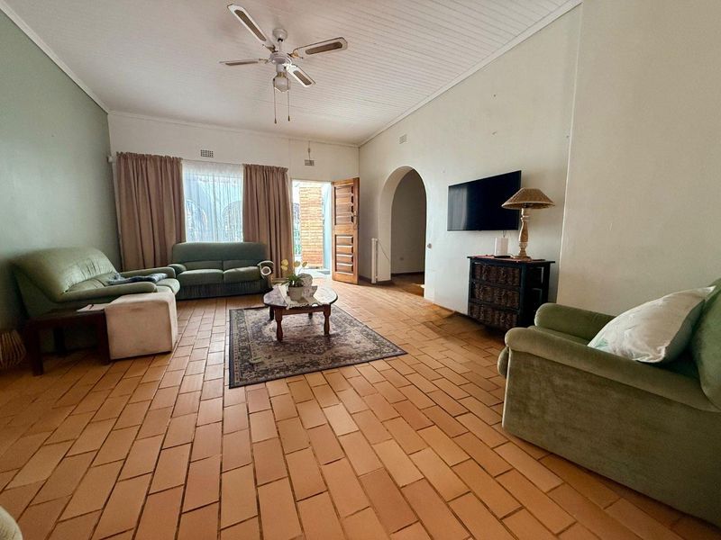 Spacious living room featuring terracotta tile flooring, a tongue and groove ceiling, and an arched doorway leading to adjacent areas.