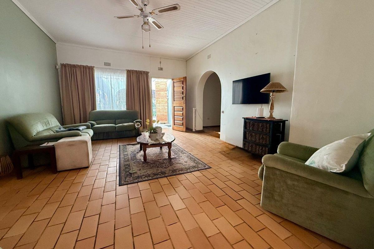 Spacious living room featuring terracotta tile flooring, a tongue and groove ceiling, and an arched doorway leading to adjacent areas.