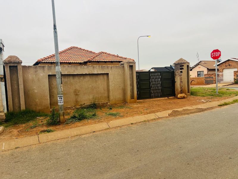Front view of the property featuring a perimeter wall, metal gate, and tiled roof structure.